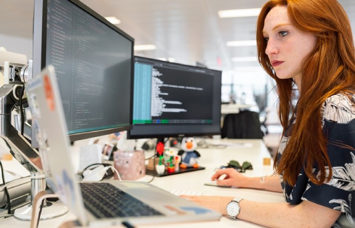 A woman in an office researching customer journey orchestration tools on her computer